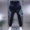 Men’S Long Pants, Casual Pants, Sports Pants, And Trendy Jogger Pants in Black, Gray, And Green Color-Blocking, Featuring a Bold And Unique Design. The Elastic Waistband with Drawstring Allows for Easy Wear And Removal, While The Tapered Fit Gives a